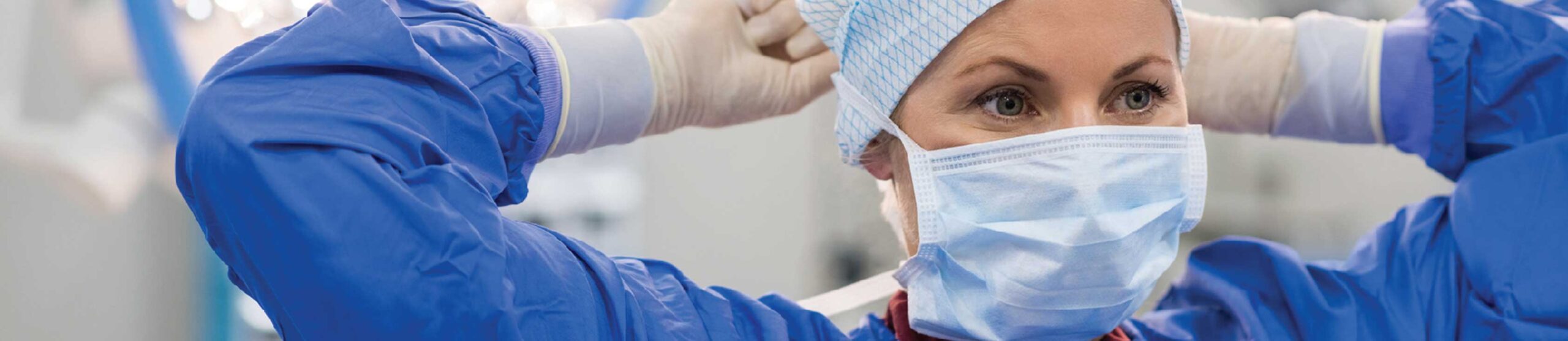 Slider-work-for-us-v2 Dr putting on face mask in blue scrubs - Work for us